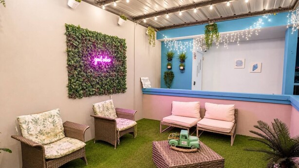 A cozy outdoor seating area with wicker furniture and a neon sign. - Private Jacuzzi • Rooftop Escape • Ponce (Ponce)