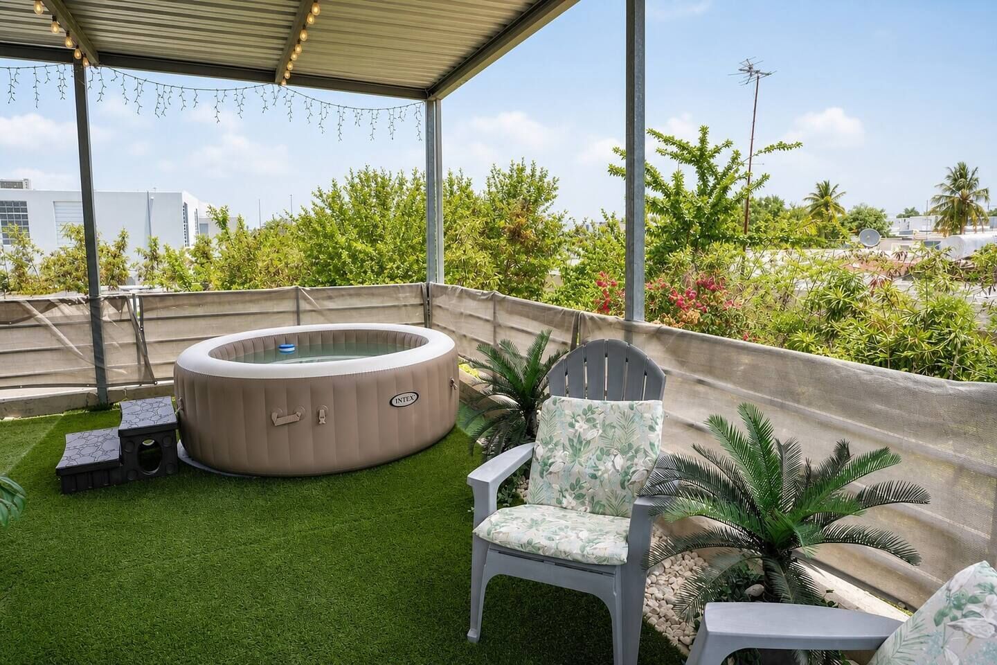 A rooftop terrace with a hot tub, a chair, and a small table.