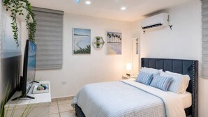 A bedroom with a bed, a TV, wall-mounted air conditioning, and artwork. - Private Jacuzzi • Rooftop Escape • Ponce (Ponce)
