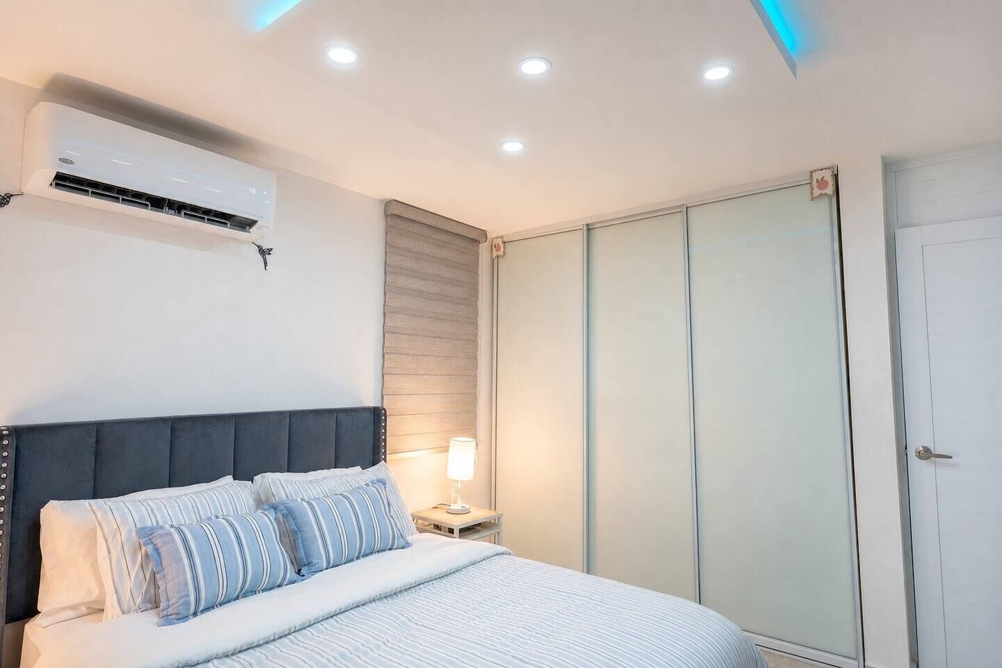 Ein Schlafzimmer mit Bett, Nachttischlampe, Klimaanlage und einem Kleiderschrank.