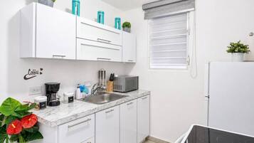Una cucina moderna con mobili bianchi, un lavello, un forno a microonde e un piano cottura.