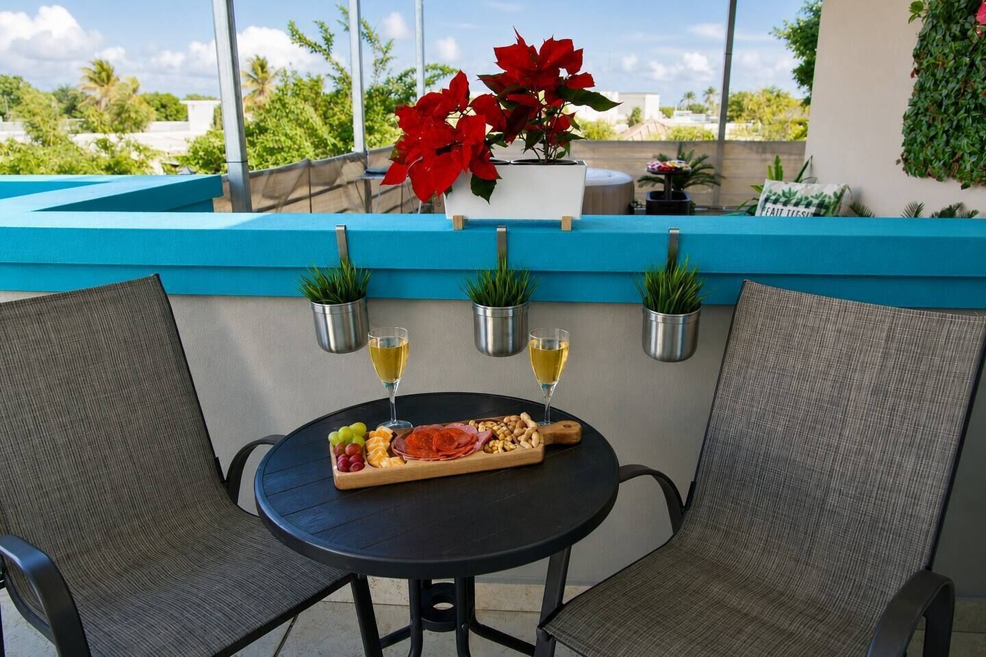 Una terraza con una mesa dispuesta para comer, rodeada de sillas y plantas en macetas.