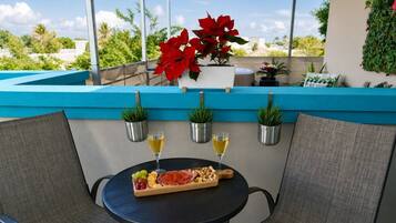 Una terraza con una mesa dispuesta para comer, rodeada de sillas y plantas en macetas.