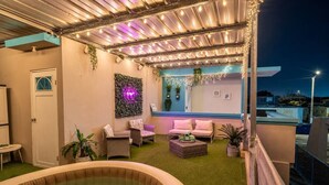 Eine Dachterrasse mit Whirlpool, Sitzgelegenheit und Lichterketten.