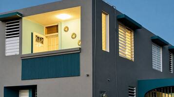 A modern two-story building with a balcony, large windows, and a flat roof.