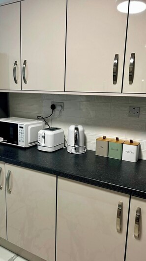 A kitchen with white cabinets, a microwave, a toaster, and a coffee maker.