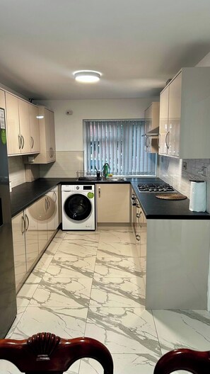 A compact kitchen with a washing machine, a sink, and a stove.