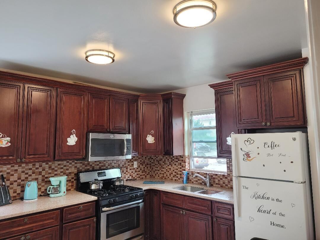 A kitchen with wooden cabinets, a microwave, a stove, and a refrigerator with decorative magnets.