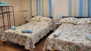 A room with two beds, a bunk bed, a chandelier, curtains, and a small table with a lamp. - BEAUTIFUL 1 BEDROOM WITH BACKYARD (FOREST HILLS)