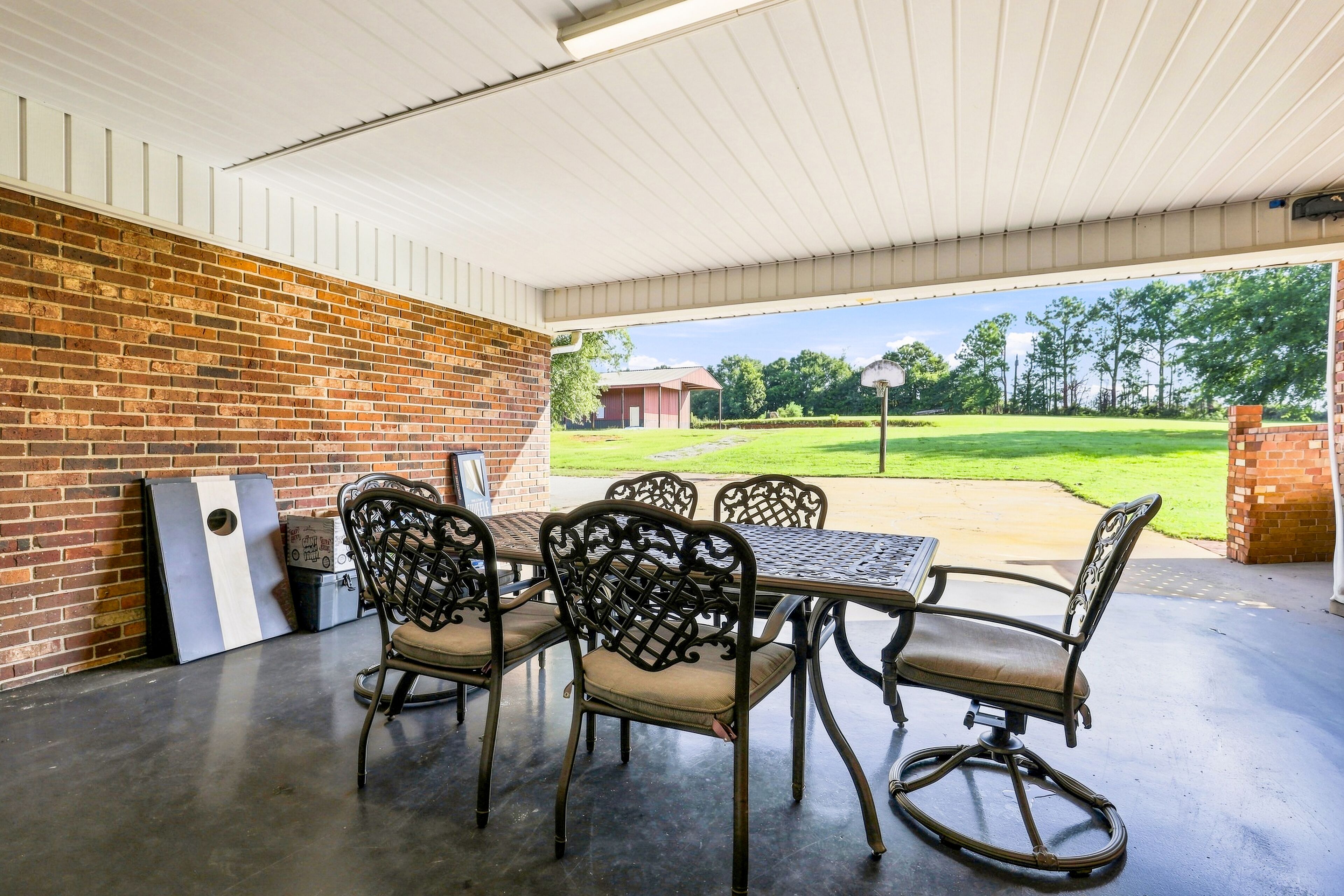 Une terrasse extérieure avec un mur en briques, une table en métal et des chaises.