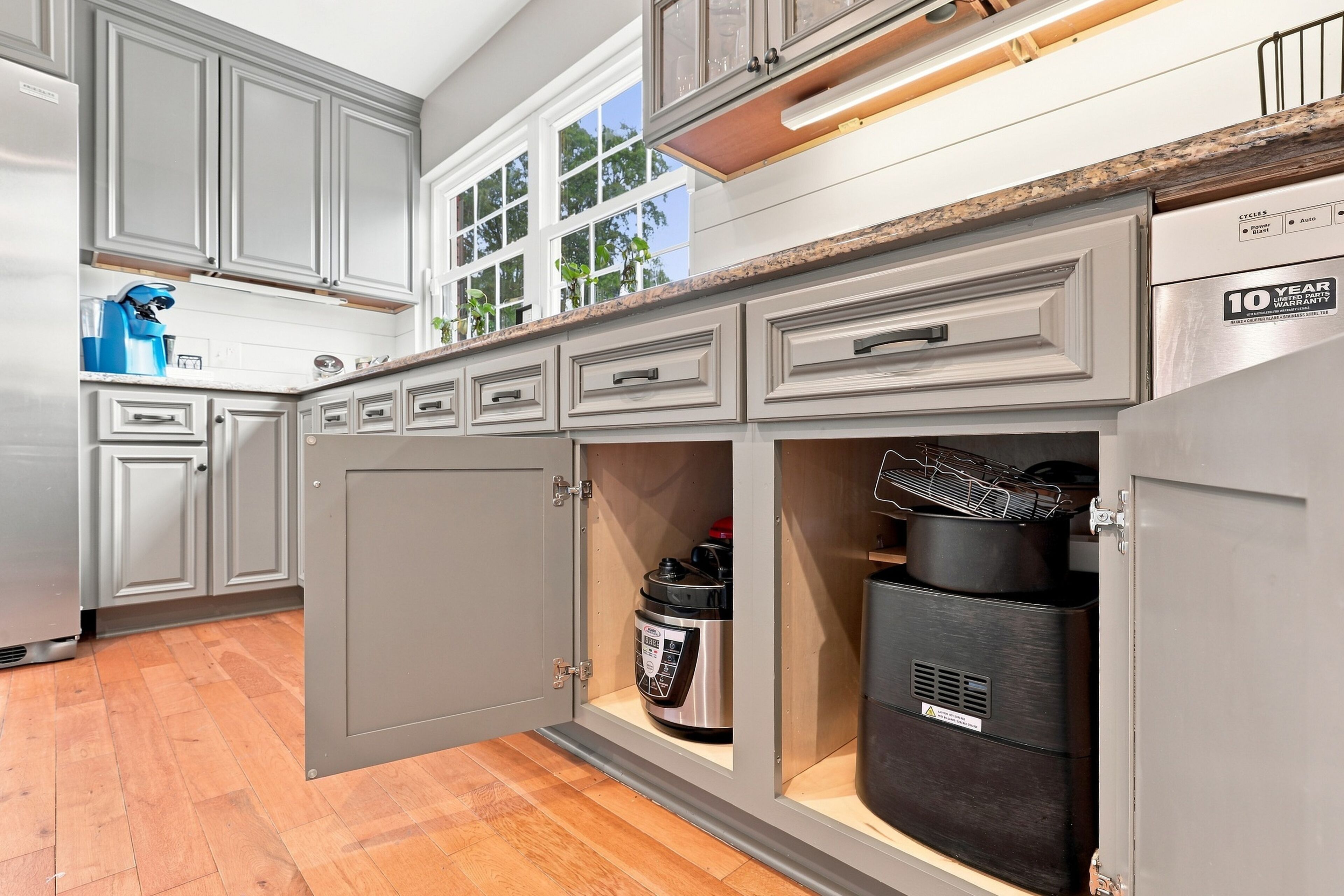 A kitchen with grey cabinets, a built-in oven, and a stainless steel range hood.