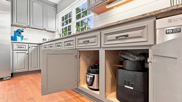 A kitchen with grey cabinets, a built-in oven, and a stainless steel range hood.