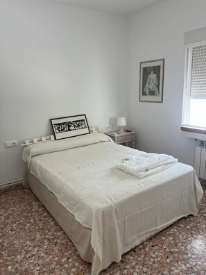 A bedroom with a bed, a nightstand, a lamp, and a window with blinds. - Villa Mercedes Pool & 5 BDRM (Calpe)