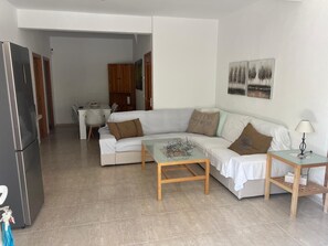 A living room with a sofa, a coffee table, and a lamp. There is a refrigerator and a cabinet in the background. - Villa Mercedes Pool & 5 BDRM (Calpe)