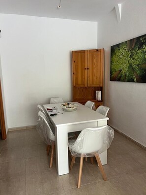 A dining area with a white table, four chairs, and a wooden cabinet. - Villa Mercedes Pool & 5 BDRM (Calpe)