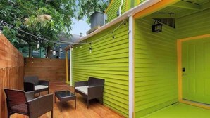 An outdoor patio with a green wall, wooden fence, and outdoor furniture. - Spacious 4-Bed NOLA Home, Pet-Friendly (New Orleans)