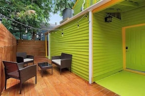 Eine Terrasse mit grüner Wand, Holzzaun und Gartenmöbeln.