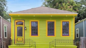 A two-story house with a front porch and a small front yard. - Spacious 4-Bed NOLA Home, Pet-Friendly (New Orleans)