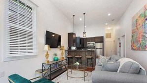 A modern living room with a sofa, a green chair, a coffee table, and a TV. - Spacious 4-Bed NOLA Home, Pet-Friendly (New Orleans)