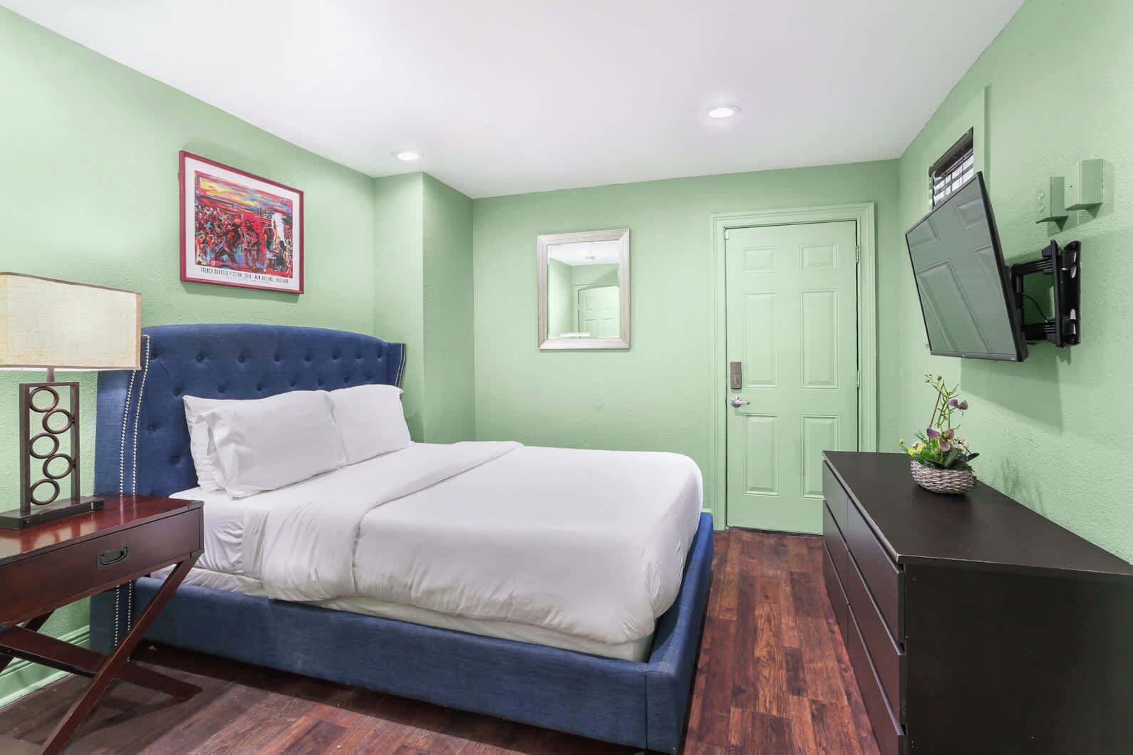 A bedroom with a bed, a dresser, a television, and a framed picture on the wall.