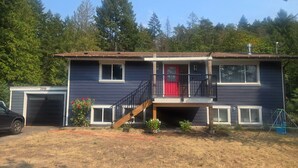 A two-story house with a red door, a covered front porch, and a garage.
