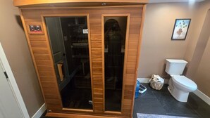 A bathroom with a wooden cabinet, a toilet, and a shower area.
