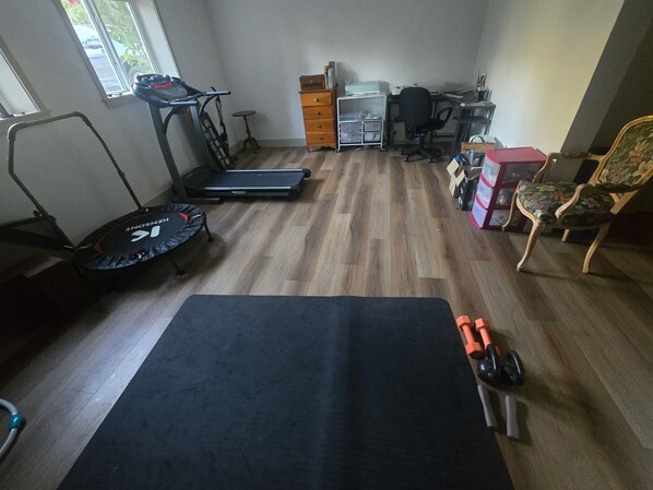 A home gym with exercise equipment including a treadmill, elliptical, and weights.