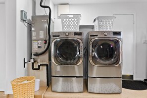 Deux machines à laver à chargement frontal en acier inoxydable, dotées d’un panneau de commande et d’une prise électrique fixée au mur.