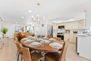 A modern kitchen with white cabinets, stainless steel appliances, and a dining area with a round table set for six. - Boutique Coastal Retreat/ Lakeview, Private Pool, Family Comfort, near AMI, IMG (Bradenton)
