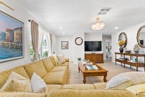 A living room with a sofa, coffee table, and a television. - Boutique Coastal Retreat/ Lakeview, Private Pool, Family Comfort, near AMI, IMG (Bradenton)