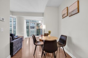A modern dining area with a round table, four black chairs, and a vase with flowers.