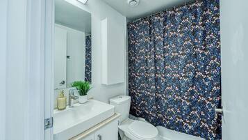 A bathroom with a white sink, a toilet, and a shower curtain with a floral pattern.