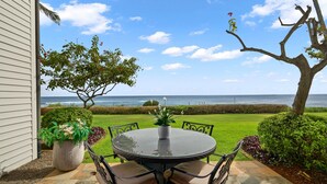 A patio with a round table and chairs, a potted plant, and a view of the ocean. - Poipu Kapili Condo 4 by Alekona Kauai - 2BR Oceanfront (Koloa)
