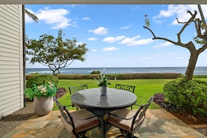 A patio with a round table and chairs, a potted plant, and a view of the ocean. - Poipu Kapili Condo 4 by Alekona Kauai - 2BR Oceanfront (Koloa)