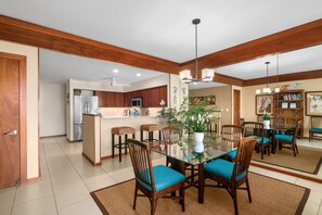 A modern kitchen with wooden cabinets, a refrigerator, and a microwave. - Poipu Kapili Condo 4 by Alekona Kauai - 2BR Oceanfront (Koloa)