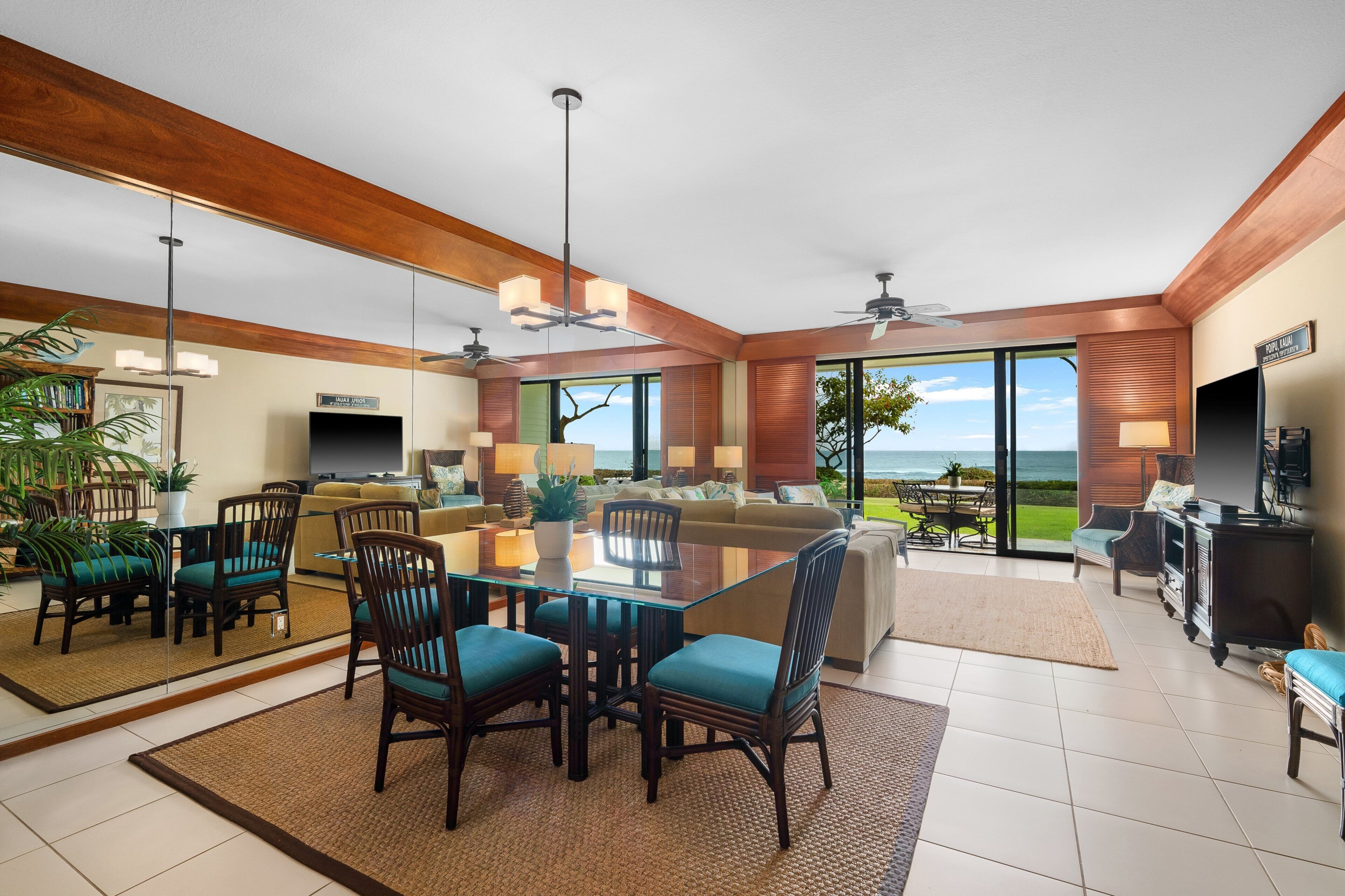 A spacious living area with a large glass door leading to a balcony, a dining area with a glass table, and a seating area with sofas and chairs.