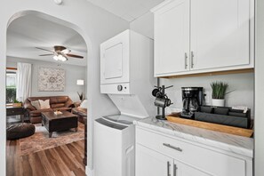 Una cocina moderna con armarios blancos, cafetera y horno integrado.