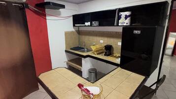 Une cuisine de taille réduite comprenant une table à manger, des chaises, un réfrigérateur et un évier.