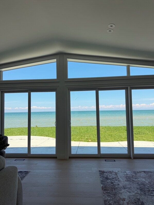 A room with large floor-to-ceiling windows offering a view of the ocean.