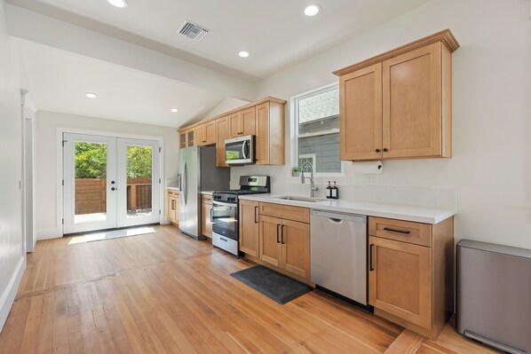 A modern kitchen with wooden cabinets, stainless steel appliances, and a large window.