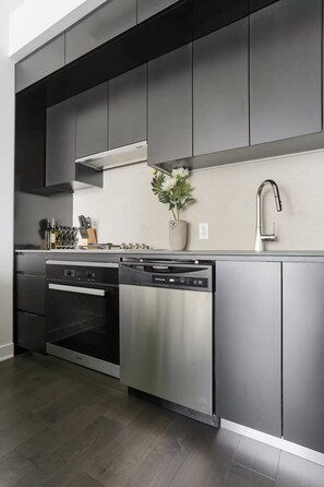 A modern kitchen with stainless steel appliances, a built-in oven, and a dishwasher. - Rare luxury penthouse/P5 Executive Collection (Montréal)