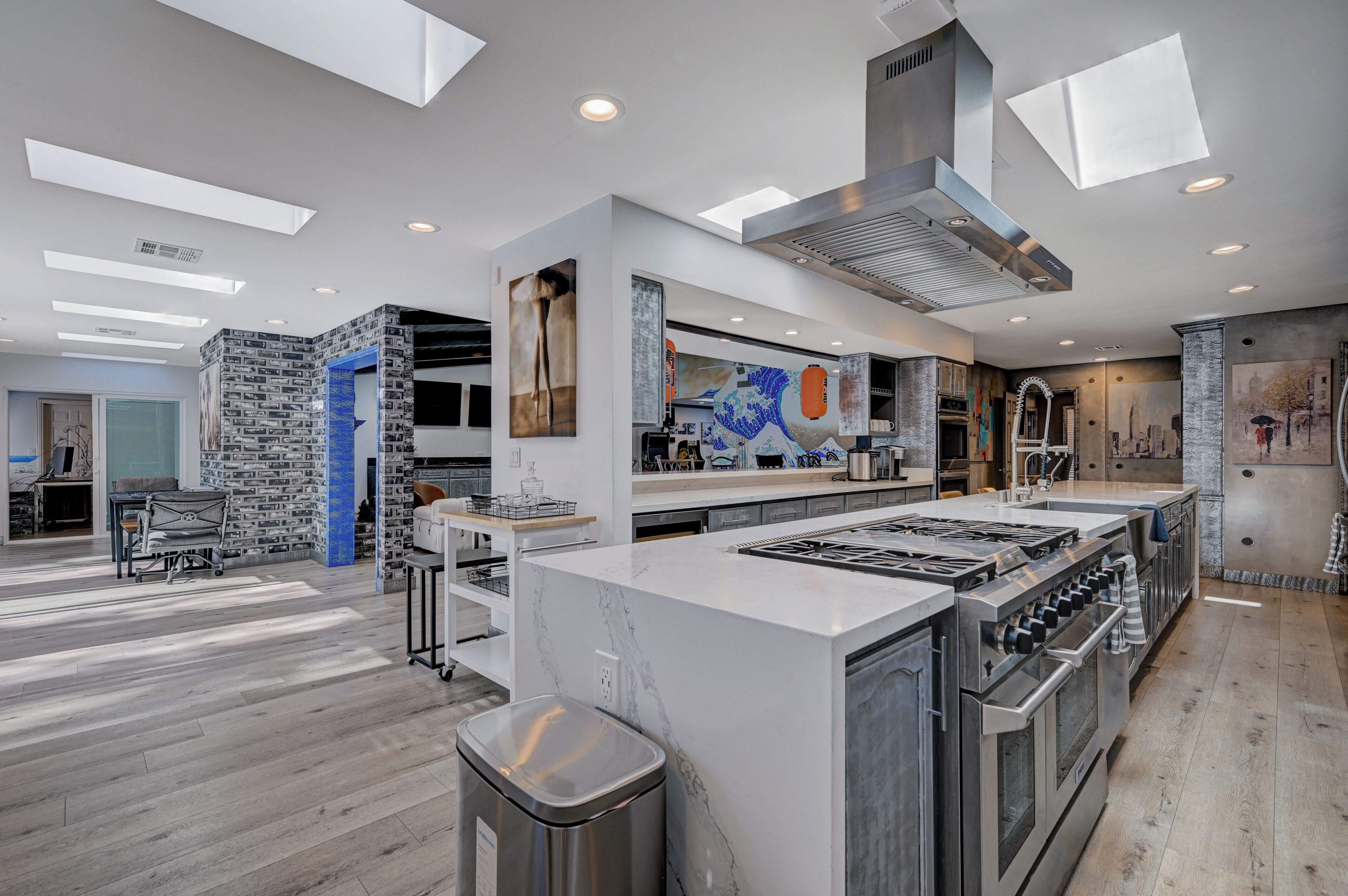 A modern kitchen with a central island, built-in ovens, and a large window above the island.