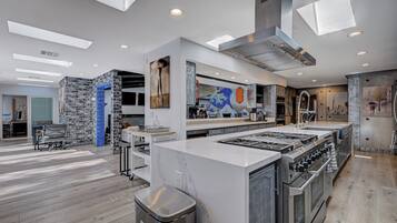 A modern kitchen with a central island, built-in ovens, and a large window above the island.