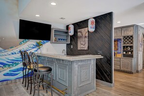 Eine moderne Küche mit Barbereich, einem flachbildfernseher über der Arbeitsplatte und einer Wand mit einem blauen Wellenmuster.