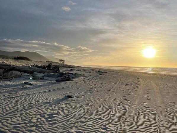 Una playa con cielo despejado y el sol poniéndose o saliendo.