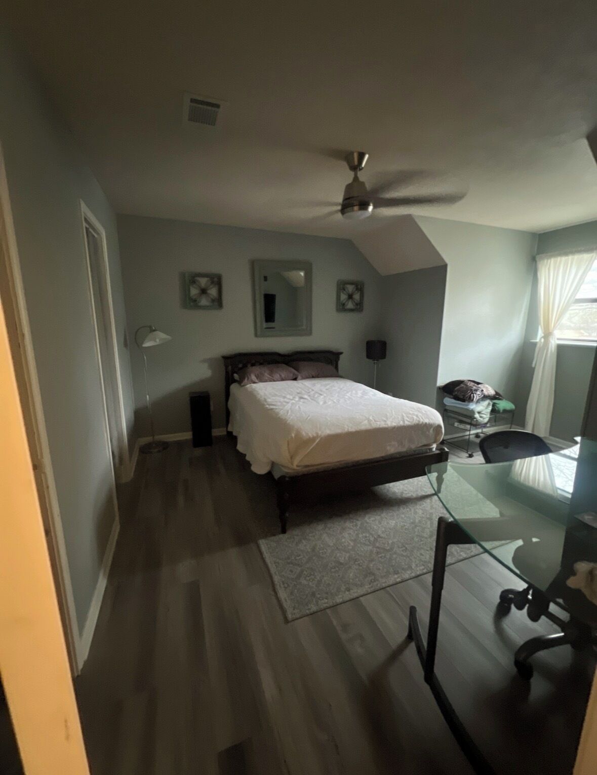 Een slaapkamer met een bed, bureau en plafondventilator.