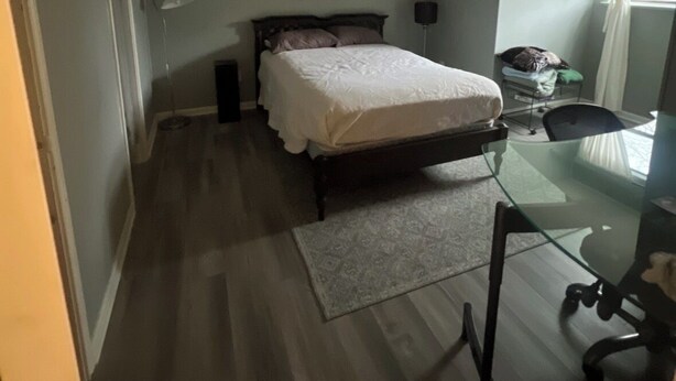 Quarto com cama, escrivaninha e ventoinha no teto.