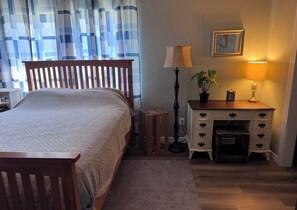 Ein Schlafzimmer mit einem Bett, einem Nachttisch, einer Lampe, einer Kommode und einem Spiegel.