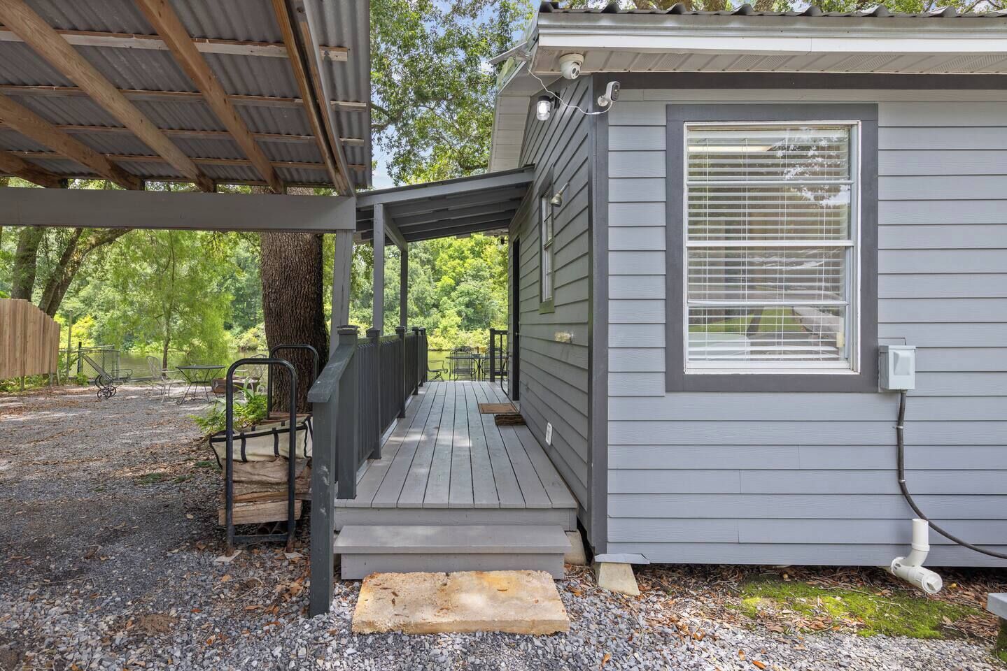 A covered outdoor area with a wooden deck, metal chairs, and a small table.