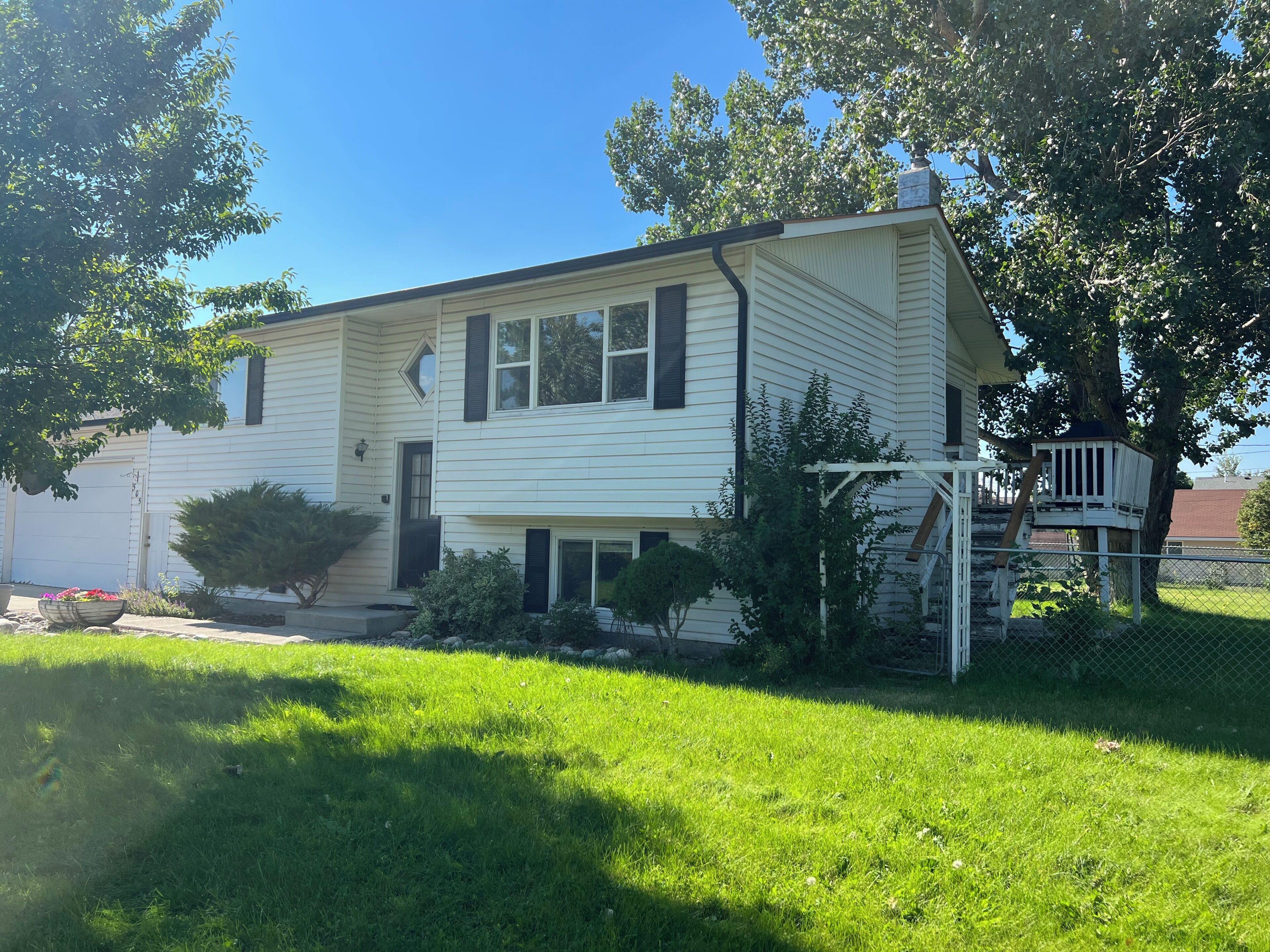 A two-story house with a front porch, a tree, and a fenced yard.